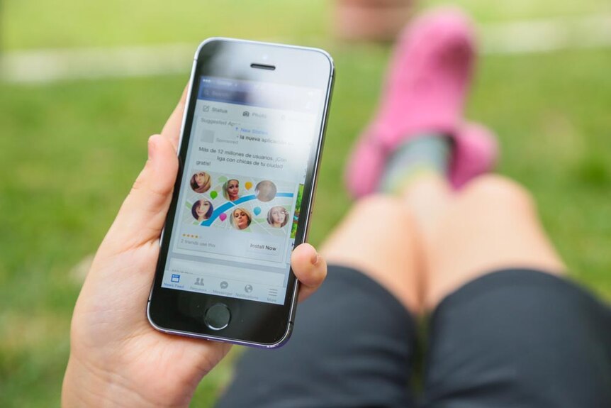 A person holding a mobile phone while lying down outdoors