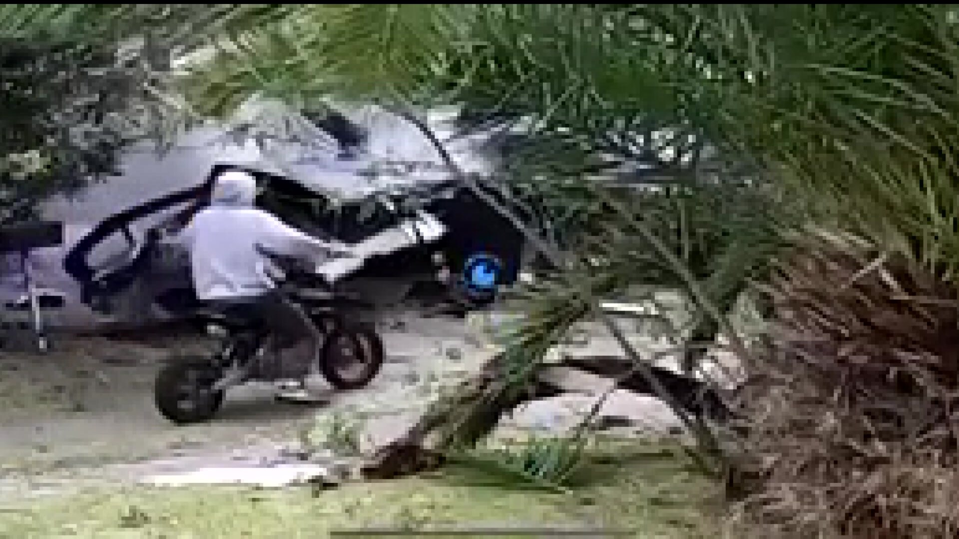 A person on a small motorbike looks at the wreckage of a car as it lies in the front lawn of a home in Ashcroft in Sydney