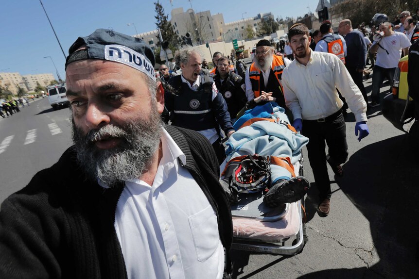 Israeli police and medics carry an injured person