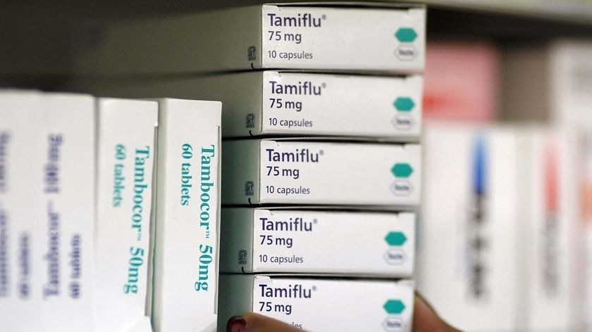 A pharmacist places boxes of Tamiflu on a shelf