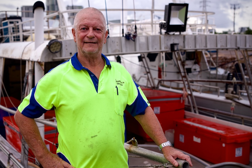 Photo of a man smiling infront of a boat.