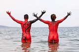 Two nude people stand in a river with red painted bodies advertising Dark MOFO's nude swim.