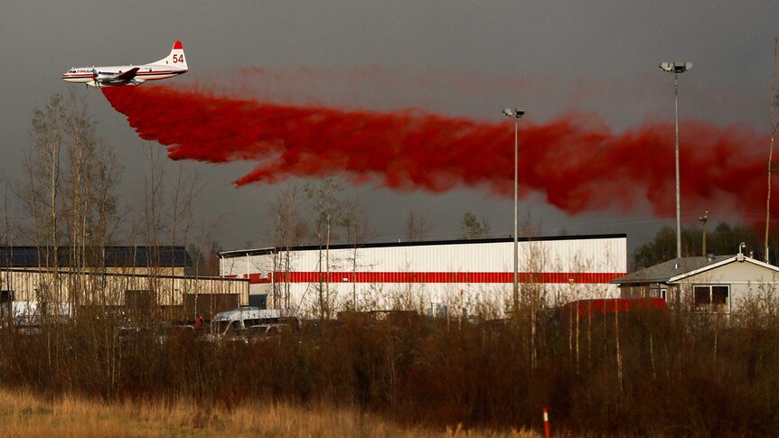A plane flies low to dump fire retardant on wildfires near Fort McMurray.