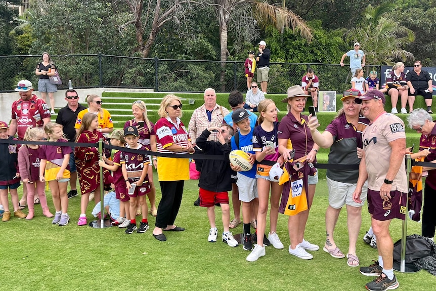 Kevin Walters stands with fans at a Broncos' training session.