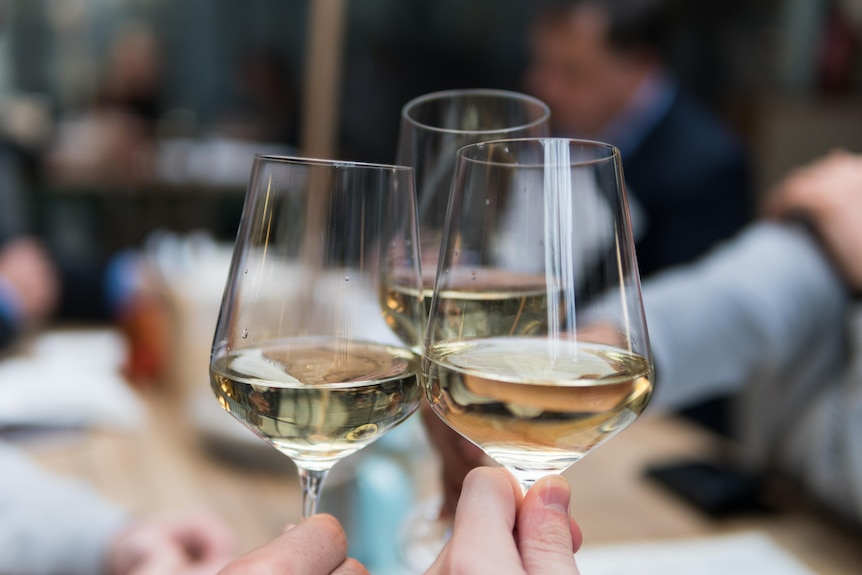 Three wine glasses containing white wine