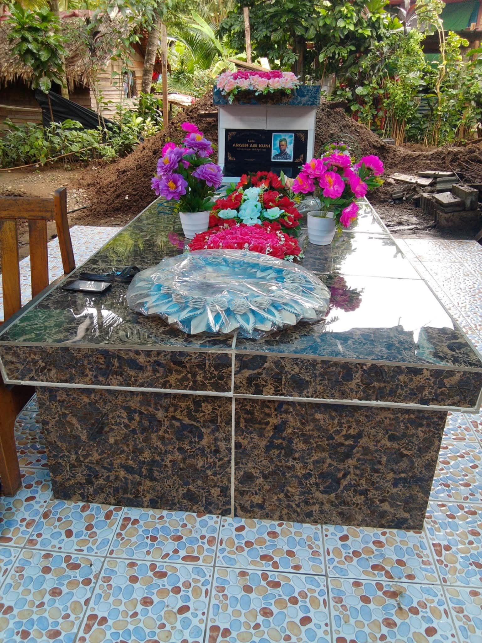 A grave with flowers and a photo of a man.