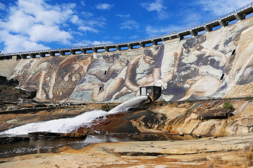 A mural painted on a massive brick dam wall