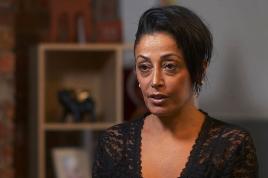 A woman wearing a black top gestures with her hands as she speaks.