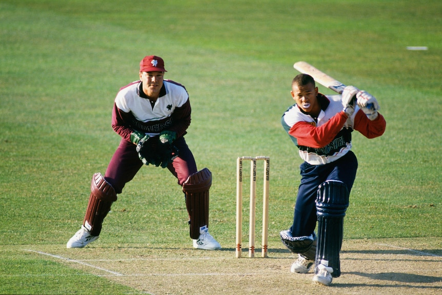 A young Andrew Symonds plays a shot. He's wearing coloured clothes and no helmet