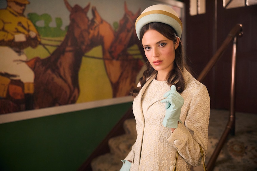 A young woman from the TV series Ladies in Black wears a hat with matching gloves and jacket