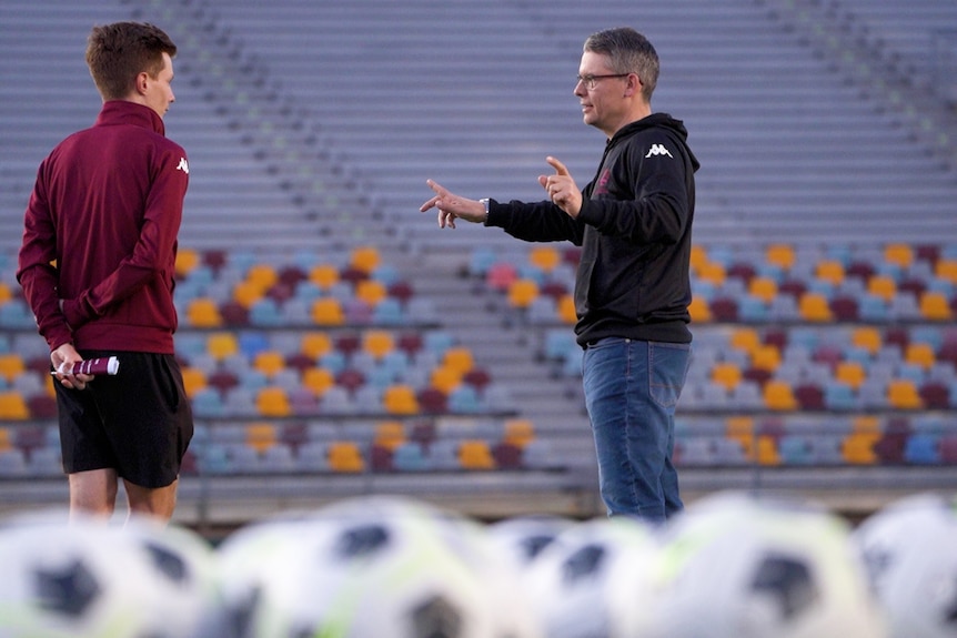 a soccer coach standing in an empty stadium