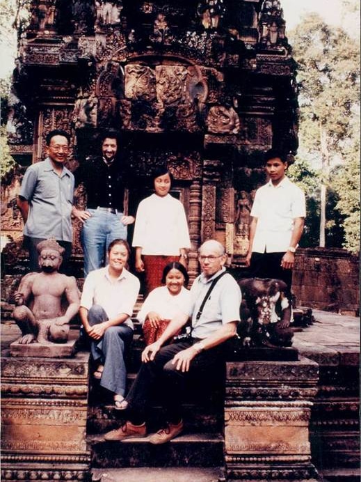 A group of people sit at a temple in Angkor Wat in Cambodia
