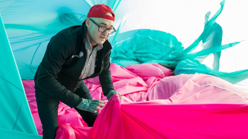 With his cap worn backwards, pilot Chris Shorten wrangles folds of fabric inside his deflating hot air balloon post-flight.