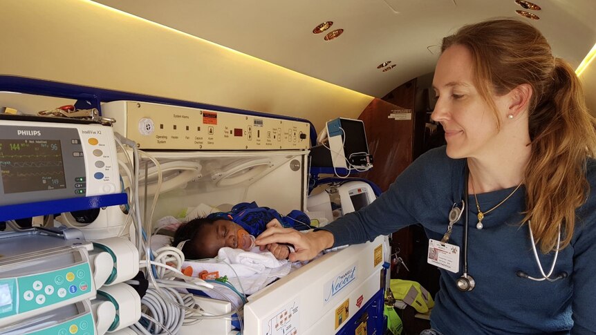 a female doctor assisting a baby in a crib