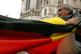 Clyde Mansell from the Tasmanian Aboriginal Council holds an Aboriginal flag