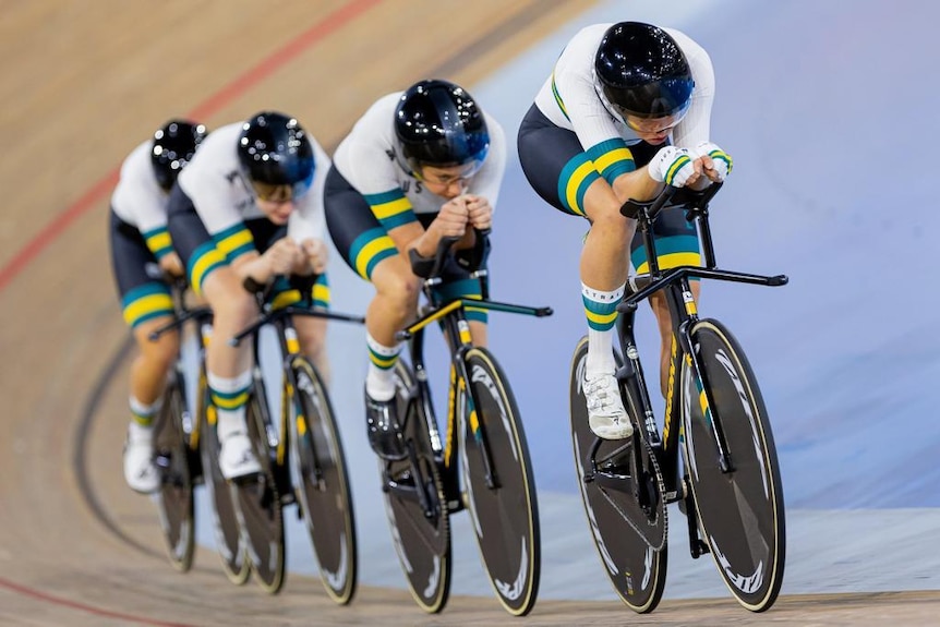 Four women cyclists are in a line in the veledrome. 