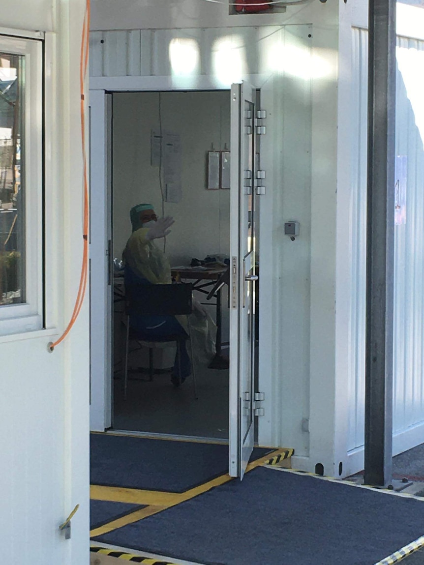 Health worker sits inside a shipping container.