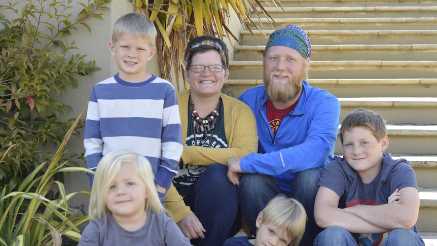 Picture of Krista and Evan Mullins and their children, Thatcher, 11, Levi 8, Finn 6, and Pepper, 4 sitting in a garden.