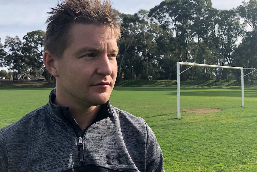 Social worker, Daniel Wright, standing next to a goal on a soccer field