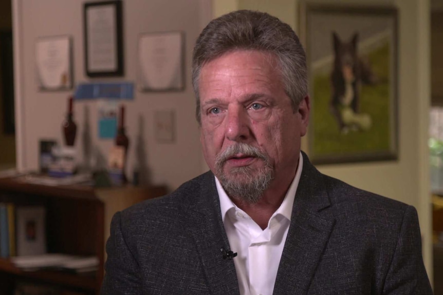 MCU of former Boeing Quality Manager John Barnett sitting in his house wearing a white open collared shirt and grey jacket