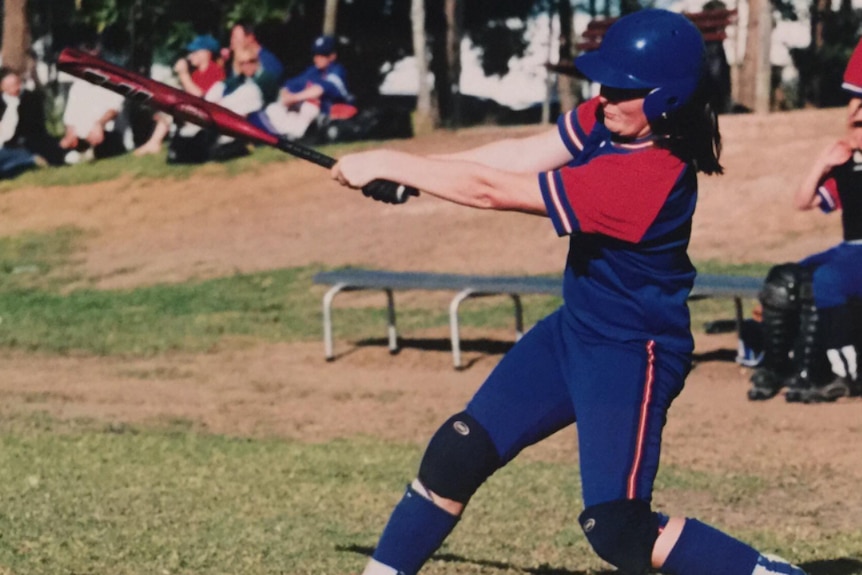 A young girl swings a bat in a softball game