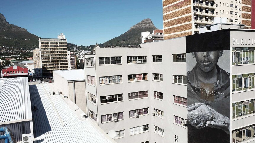 A Cape Town city scape showing a mural of a young boy with his hands extended.