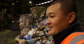 Man stands in front of mound of rubbish