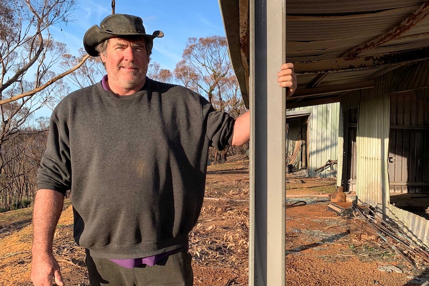 Barry Smith standing next to a fire-damaged building on Kangaroo Island