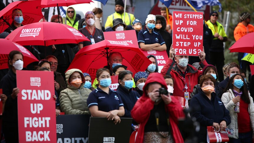 Workers holding red umbrellas and signs saying 'stand up and fight back'