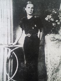 An historic black and white studio photo of a slim young woman in a dark dress.