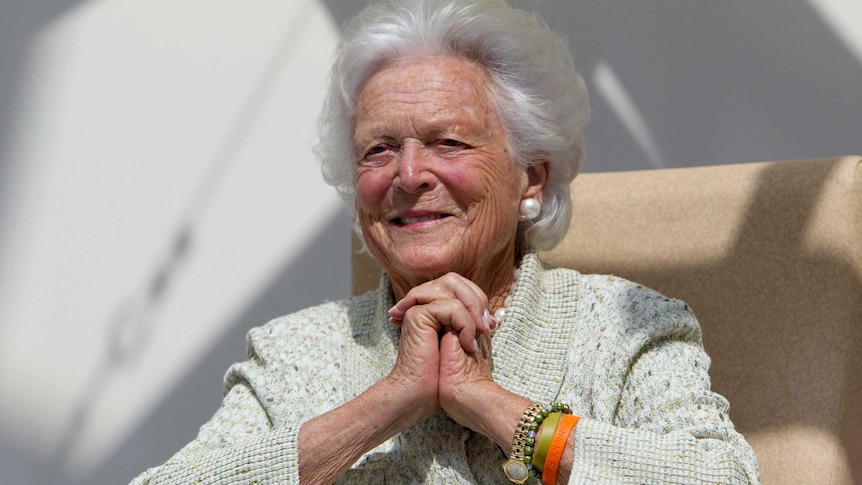 Former first lady Barbara Bush clasp hands.