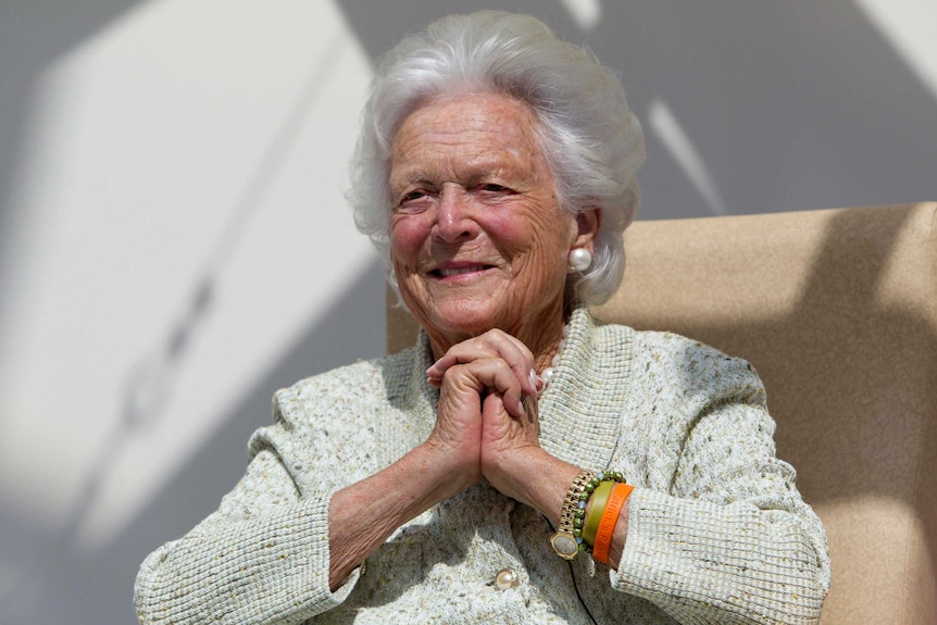 Former first lady Barbara Bush clasp hands.