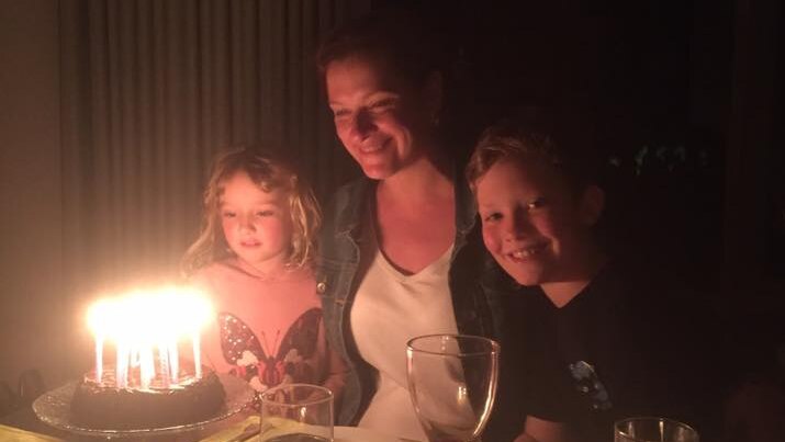 A woman and two children with a birthday cake