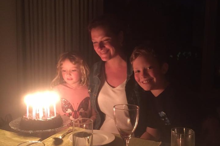 A woman and two children with a birthday cake