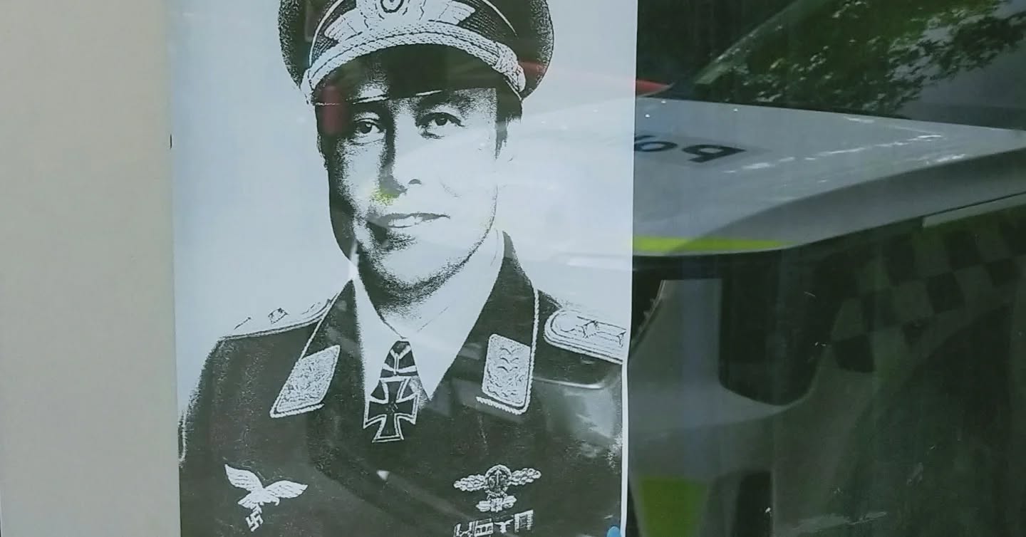 Un cartel que muestra a Elon Musk con uniforme nazi cuelga en el escaparate de un café en Canberra.