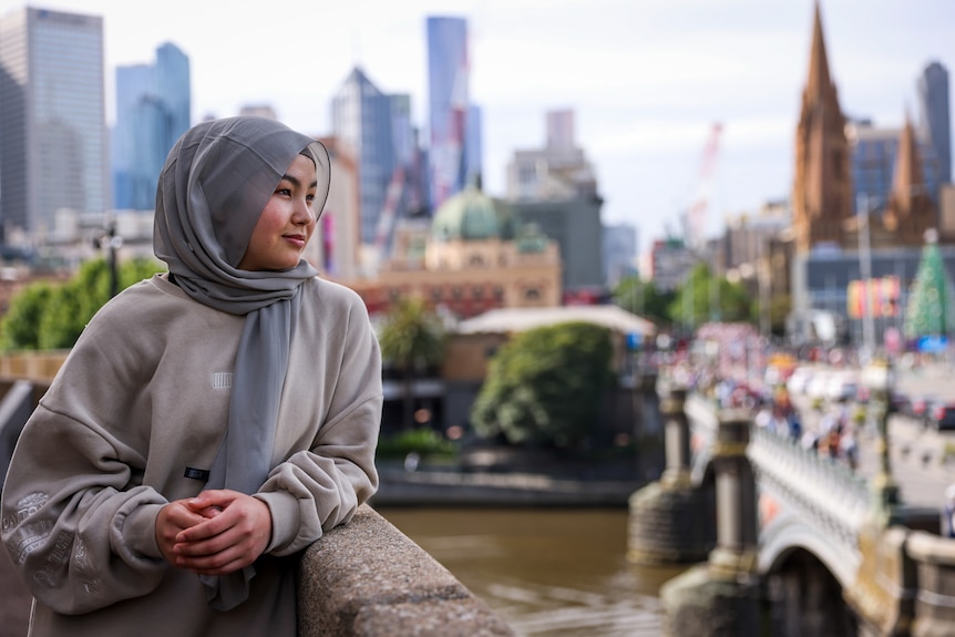 Adiba looks out from a balcony at Melbourne's Arts centre with the Yarra River and Flinders Street station in the background