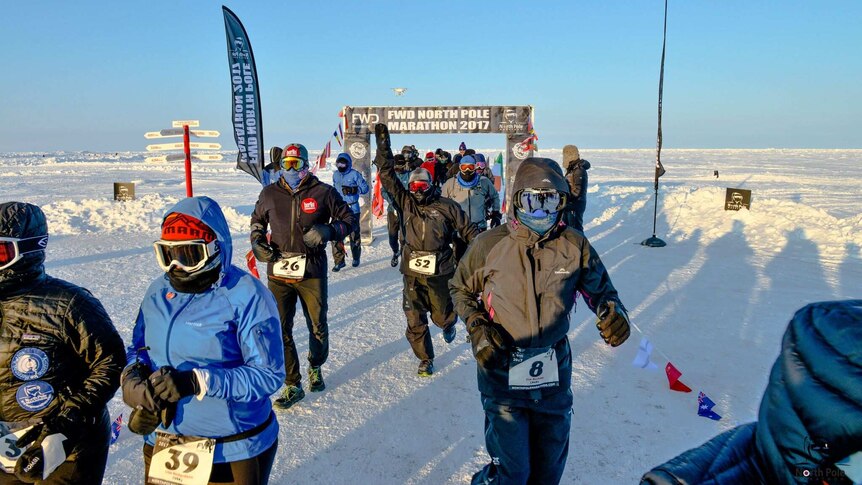 A group of people dressed in protective winter clothing pass through the start gates at the North Pole Marathon.