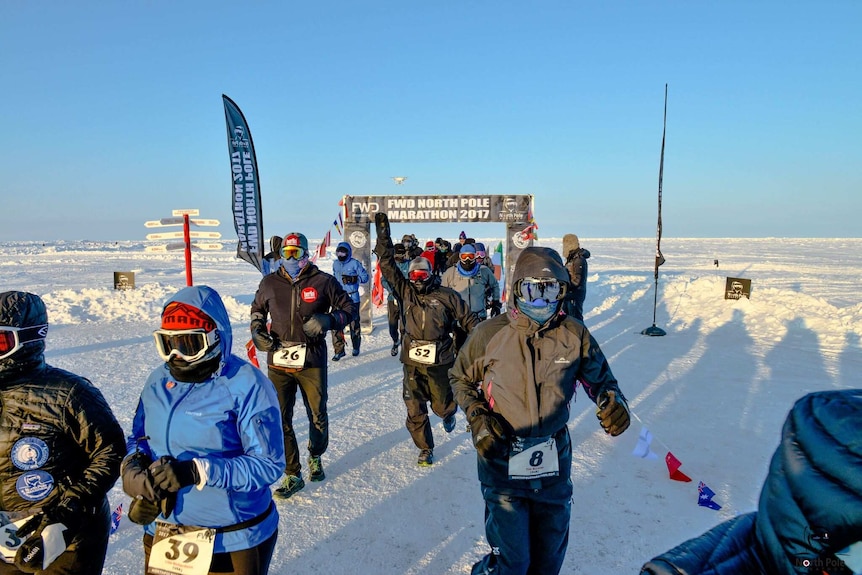 A group of people dressed in protective winter clothing pass through the start gates at the North Pole Marathon.