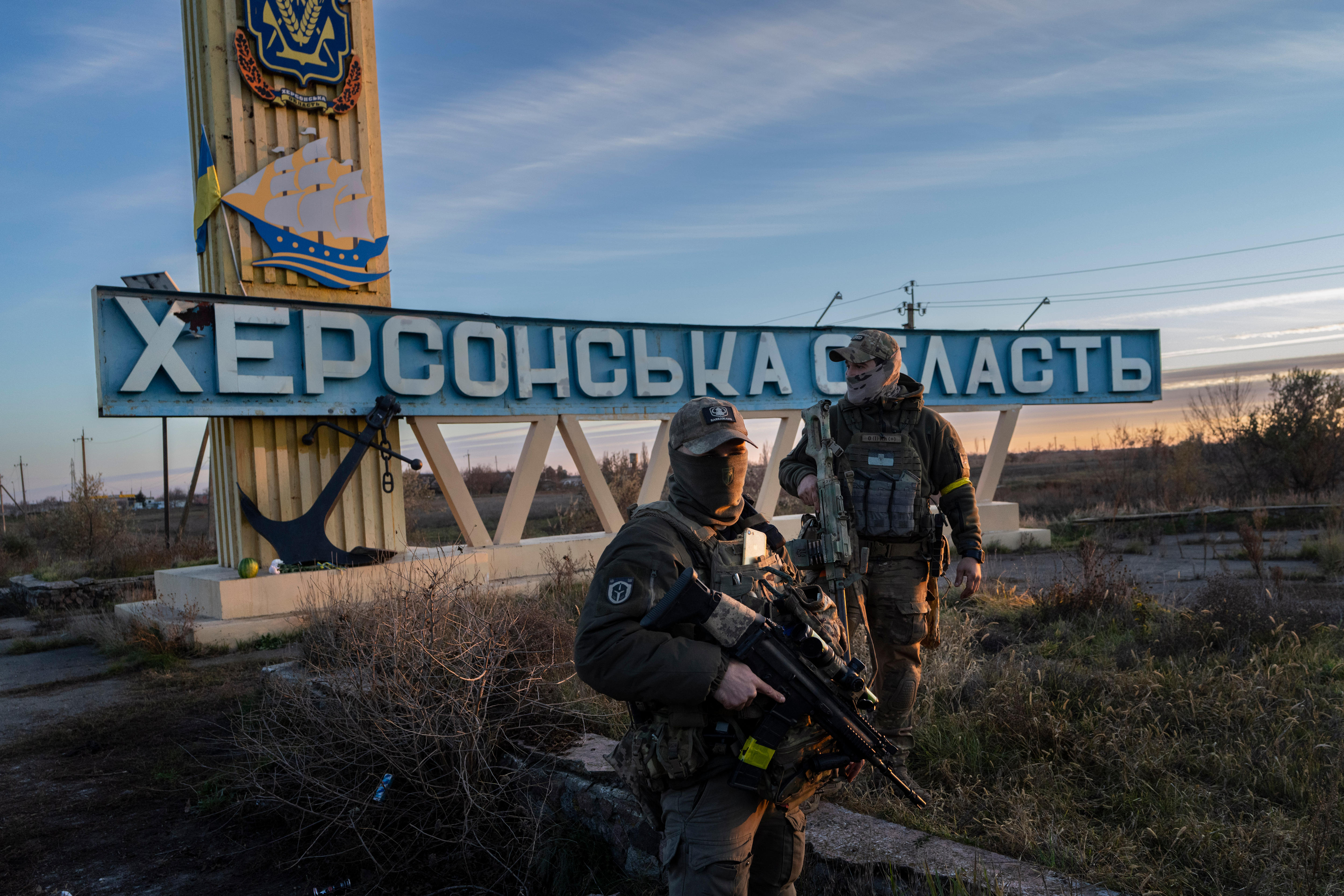 Two soldiers in front of a sign which reads "Kherson region"