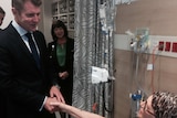 NSW Premier Mike Baird shakes the hand of a cancer patient in a treatment centre.