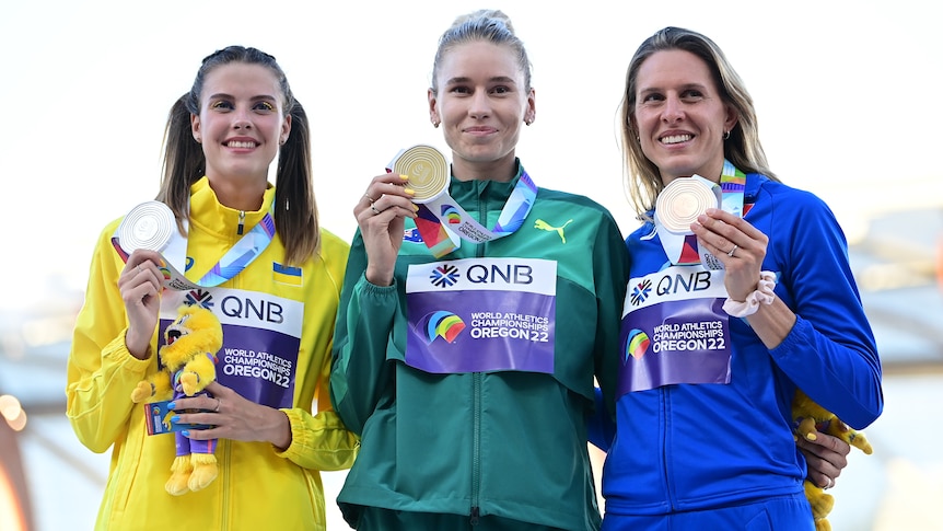 Three female high jumpers show off their medals at the World Athletics Championships.