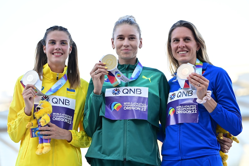 Three female high jumpers show off their medals at the World Athletics Championships.