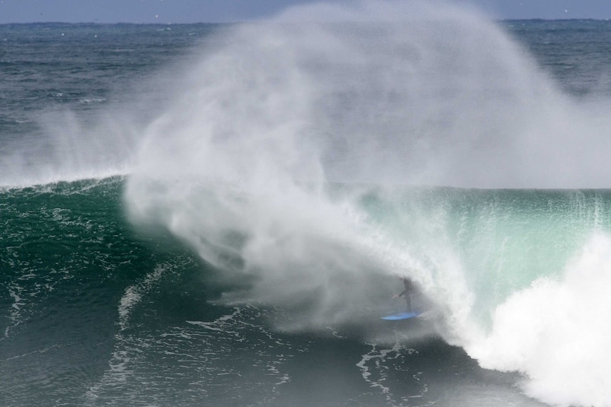 surfer getting blown out of the barrel of the wave surrounded by spit and spray from the wave