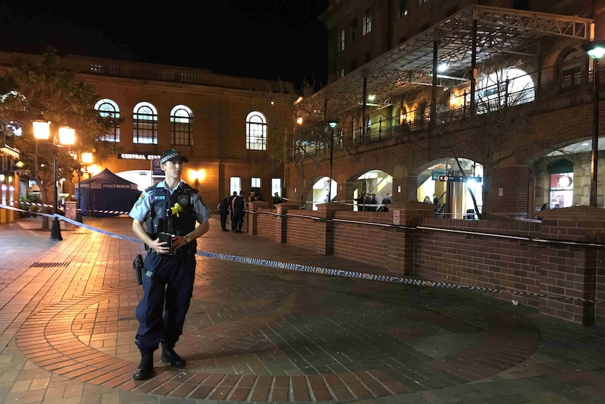 Cop stands in front of police tape.