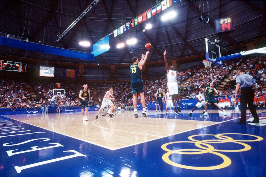 wide and low photo of a basketball court at the 2000 olympics with a crowd present