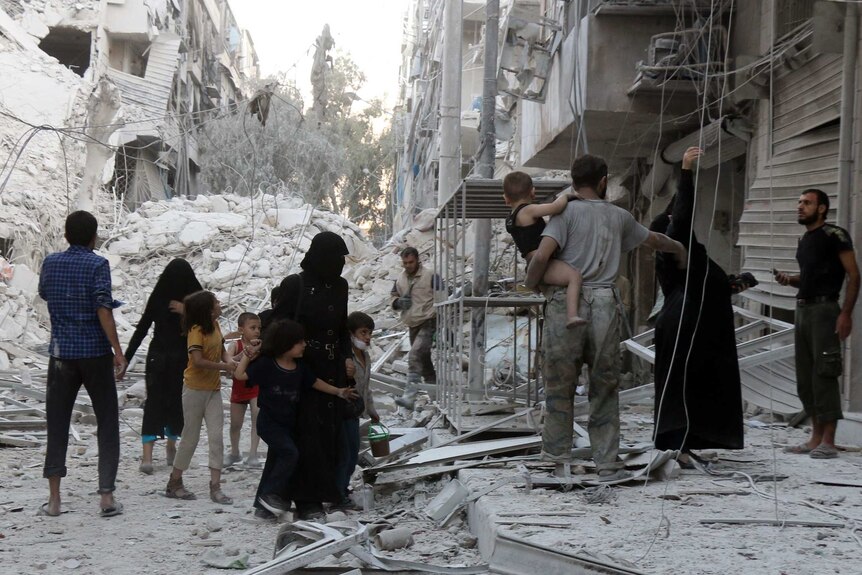 A Syrian family leaves the area following a reported airstrike on September 23, 2016, on the al-Muasalat area in the northern Syrian city of Aleppo