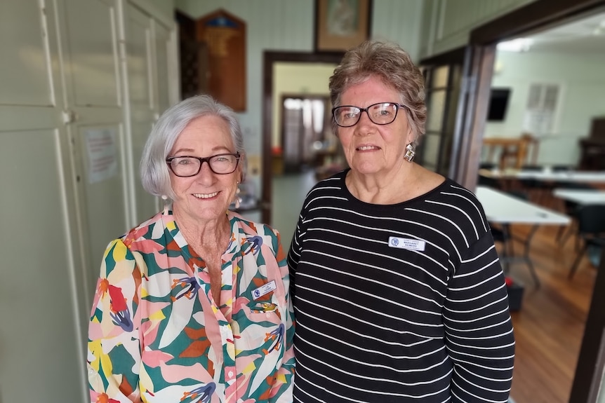 Two women in glasses smiling inside a town hall 