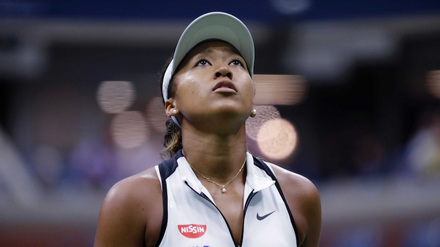 A tennis player stares up at the big scoreboard as she is down in a match at the US Open.