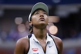 A tennis player stares up at the big scoreboard as she is down in a match at the US Open.