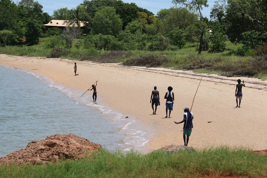 Men go spear fishing along the beach in Maningrida.